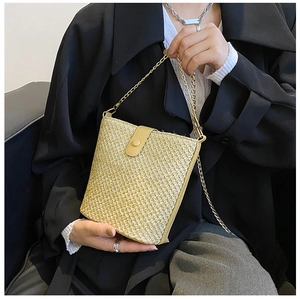 Detail van handgeweven strooien emmertas met gouden ketting en lederen gespsluiting