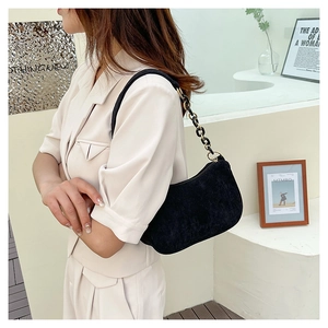 Detail of black corduroy shoulder bag with resin and metal chain strap on model