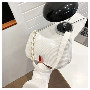 Close-up of white corduroy shoulder bag with acrylic and gold metal chain strap detail