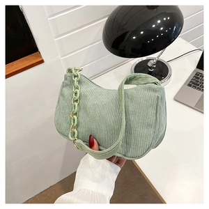 Detail of light green corduroy underarm bag with decorative plastic chain strap