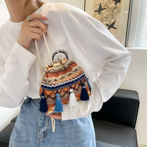 Sac seau tissé bohème avec motifs géométriques et pompons colorés porté par mannequin