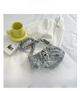 Macro view of pleated cloud bag texture with floral silver chain on white fabric