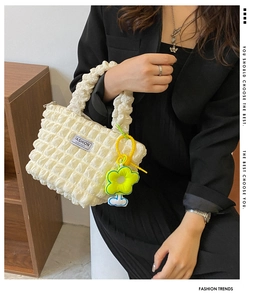 Detail of off-white pleated fabric handbag with yellow sunflower charm and logo tag