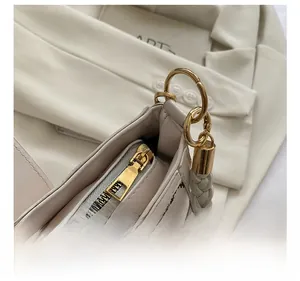 Close-up of beige leather bag featuring woven handle and gold zipper hardware detail