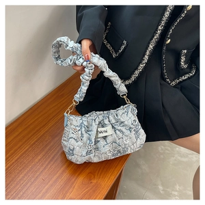 Detail of light blue pleated cloud bag with silver heart chain and branded fabric tag