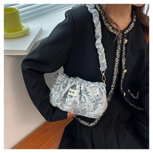 Detail of light blue cloud bag featuring silver floral chain and pleated shoulder strap