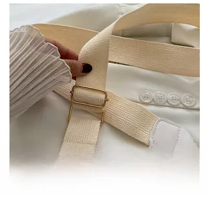 Macro shot of adjustable woven strap with gold metal buckle on beige quilted handbag
