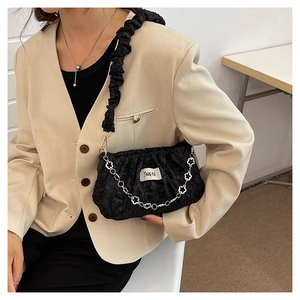 Detail of black pleated cloud bag with silver flower chain and fabric label branding