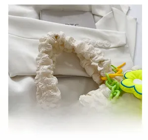 Detail of creamy white bubble textured tote bag with green chain and floral charm