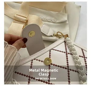 Detail of white quilted bag with magnetic gold snap closure and woven handle