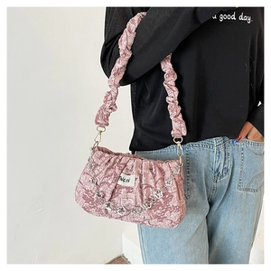 Detail of pink pleated cloud bag featuring silver floral chain and brand logo tag
