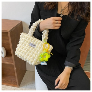 Detail of cream pleated bubble fabric bag with yellow flower pendant and fashion label