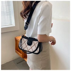 Detail view of white quilted bag with brown diamond pattern and black woven strap