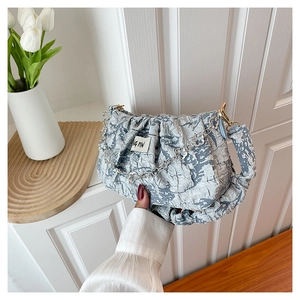 Close-up of light blue pleated cloud bag featuring jacquard texture and silver floral chain