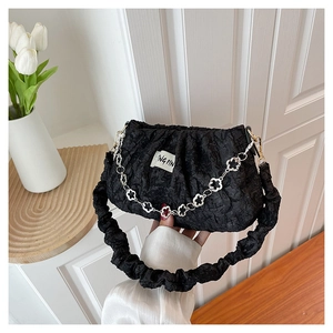 Detail of black pleated cloud bag with silver flower chain and fabric label texture
