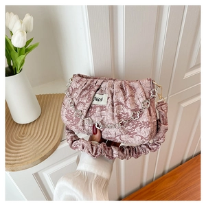 Detail of a dusty pink ruched cloud bag with silver flower chain and JINGIN label