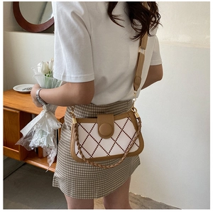 Detail of rhombic pattern crossbody bag with brown trim and stylish woven handle strap