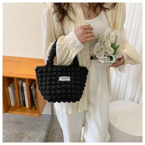 Close-up of black quilted bubble handbag featuring a fashion instinct brand label detail