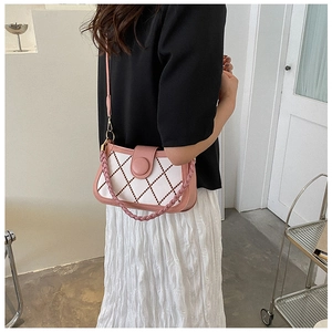 Detailed side view of pink and white quilted shoulder bag with woven handle on a model