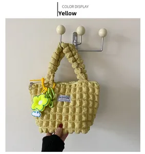 Detail of yellow bubble pleated shoulder bag with floral charm and green chain strap