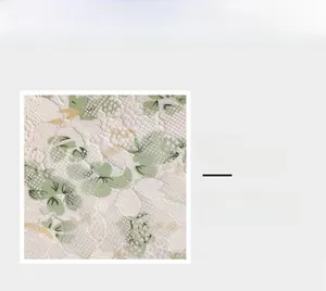 Macro shot of white lace fabric with green floral embroidery and mesh texture
