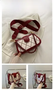 Detail of red quilted crossbody bag with plaid embroidery and circular decorative clasp