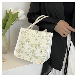 Close-up of green floral lace handbag with white braided handles in elegant lifestyle setting