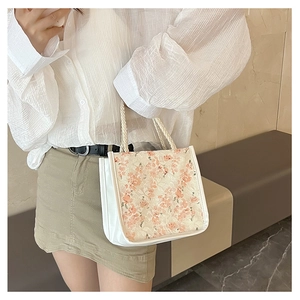 Close-up of floral embroidery texture and white woven handles on a canvas tote bag