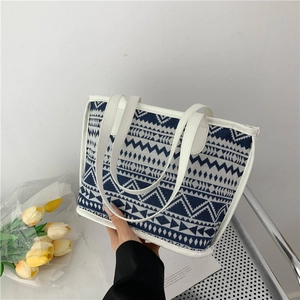 Detail van de canvas shopper met blauwe geometrische patronen en witte leren handvaten