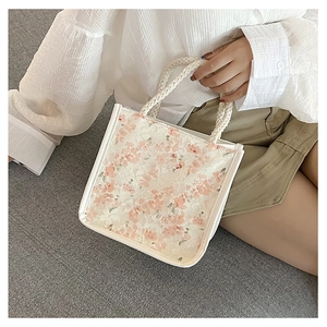 Close-up of small floral lace handbag with pink flowers and white woven rope handle
