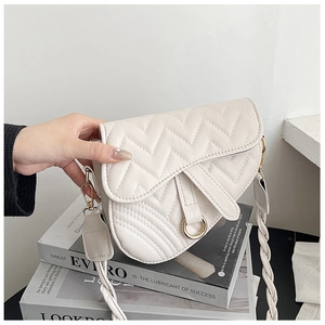 Detail of cream saddle bag featuring wave stitching, gold metal ring and woven strap