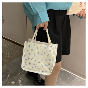 Detail view of the floral canvas tote bag featuring blue flower patterns and rope handles