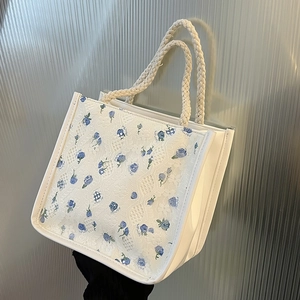 Detail of white lace handbag featuring delicate blue floral patterns and rope handles