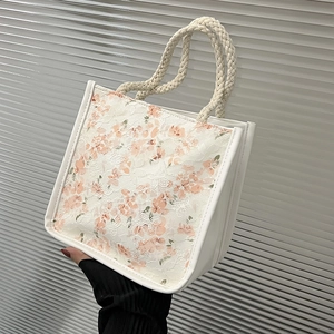 Detail of floral lace fabric and woven rope handle on a stylish canvas tote bag