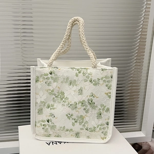 Detail of white lace floral tote bag with green accents and woven rope handles