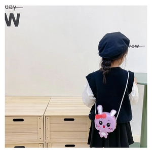 Detalle de un bolso bandolera infantil con forma de conejo morado y lazo rojo en relieve