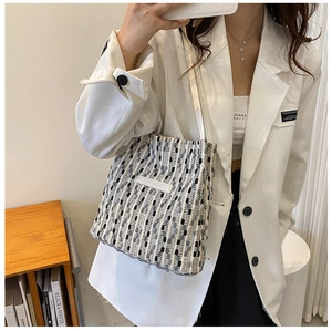 Dettaglio di una borsa tote in tweed intrecciato con sottili spalline bianche