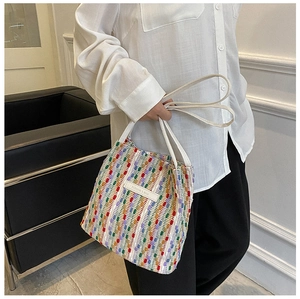Dettaglio della borsa tote intrecciata colorata con etichetta in pelle bianca e manici