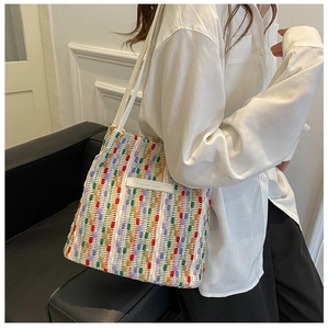 Dettaglio della borsa tote intrecciata a righe colorate con tracolla bianca
