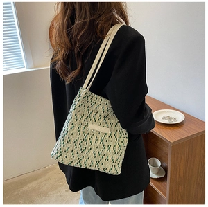 Dettaglio borsa tote tessuta con motivi geometrici verde e bianco e spalline color crema