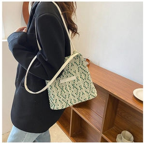 Dettaglio della borsa a mano intrecciata verde e beige con tracolla in pelle bianca