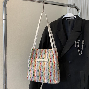 Dettaglio della borsa tote intrecciata colorata con manici bianchi ed etichetta moda