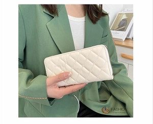 Dettaglio del portafoglio lungo trapuntato color crema con zip tenuto da una modella