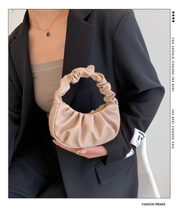 Detail of apricot pleated cloud bag paired with black suit for a stylish fashion look