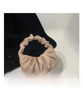 Detail of beige pleated cloud bag with soft faux leather texture and crescent moon shape