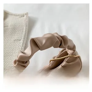 Detail of the pleated handle and gold chain strap on the beige PU cloud handbag
