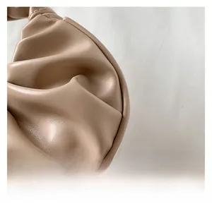 Detailed macro view of the beige pleated texture and soft leather grain on the handbag