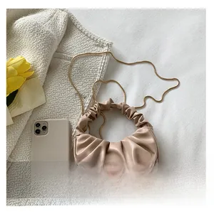 Detail view of small pleated cloud bag in beige PU leather with gold chain and tulip