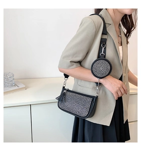Detail of black underarm bag with silver studs, fringe tassel and mini coin purse