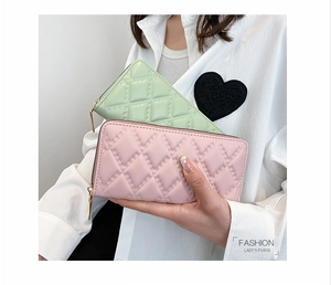 Dettaglio di portafogli lunghi in pelle trapuntata verde menta e rosa con zip oro